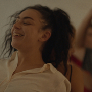 A still from Erupcja of a woman in a cream shirt in with dark hair in foreground, two others blurred in background.