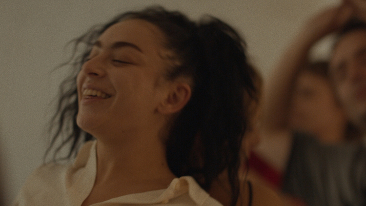A still from Erupcja of a woman in a cream shirt in with dark hair in foreground, two others blurred in background.