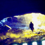 An over-exposed photo of a silhouette of a man walking through an icy cave.
