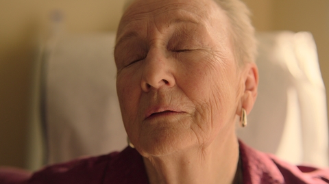 A woman with her eyes closed sitting up in bed.