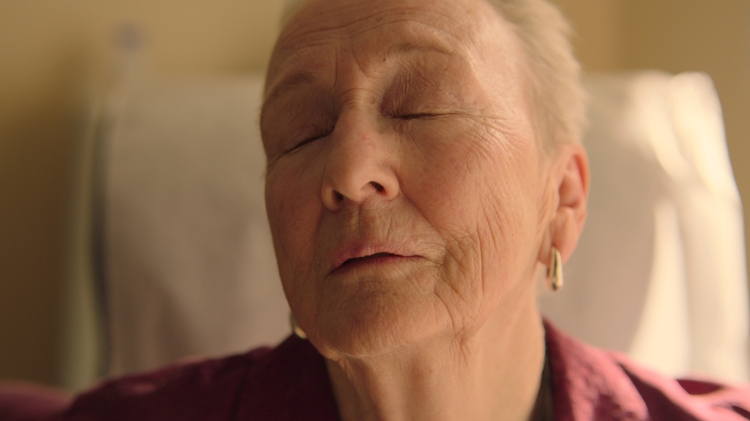 A woman with her eyes closed sitting up in bed.