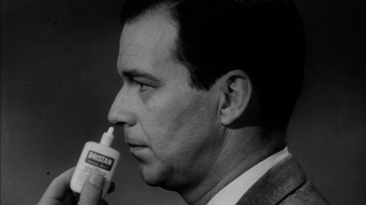 A still from The Movie Orgy - black and white photo of a man in a suit applying Dristan nasal spray to his nose.