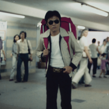 Person with a large backpack standing in a busy indoor transit area.