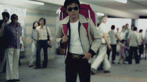 Person with a large backpack standing in a busy indoor transit area.