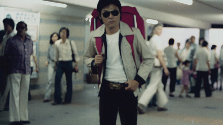 Person with a large backpack standing in a busy indoor transit area.