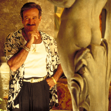 A still from The Birdcage of a man standing next to a statue.