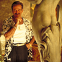 A still from The Birdcage of a man standing next to a statue.