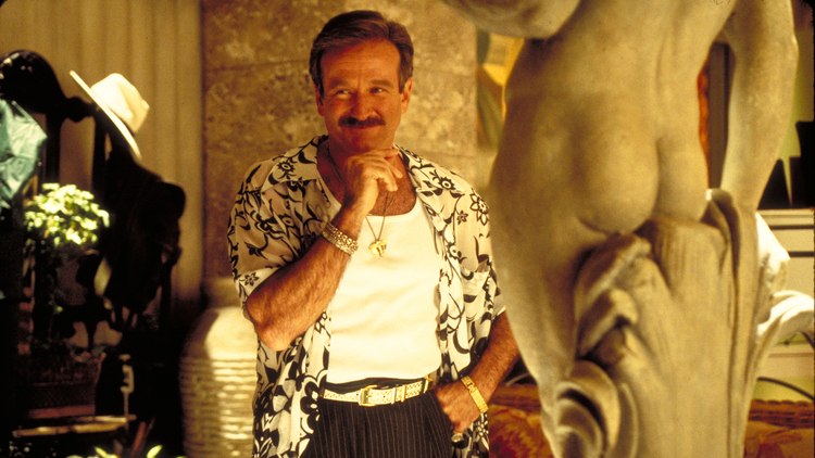 A still from The Birdcage of a man standing next to a statue.