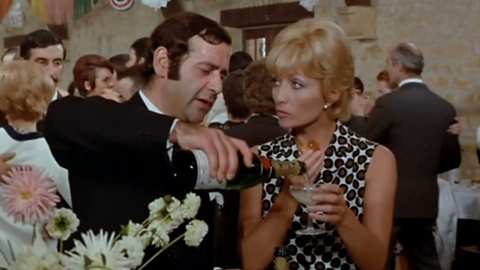 People dressed formally pouring and holding champagne glasses at a lively indoor party with floral decorations.