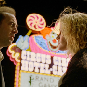 Two people look at each other in front of a neon sign for Circus Circus Hotel Casino