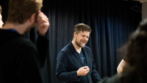 A still of a person teaching an improv class.