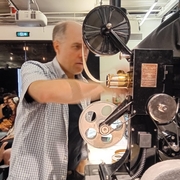 A still of Christopher Bird operating a projector.