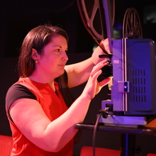 A still of Rosie Taylor operating a projector.
