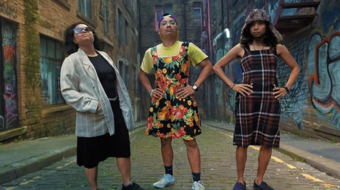 Three people standing outside looking at the camera with their hands on their hips.