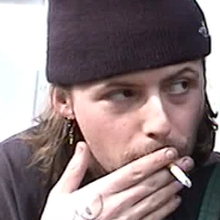 A close up of two people - one of them smoking a cigarette.