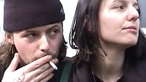 A close up of two people - one of them smoking a cigarette.