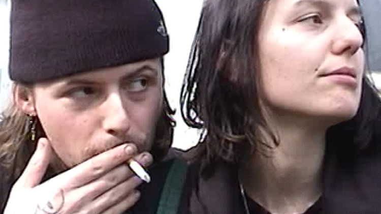 A close up of two people - one of them smoking a cigarette.