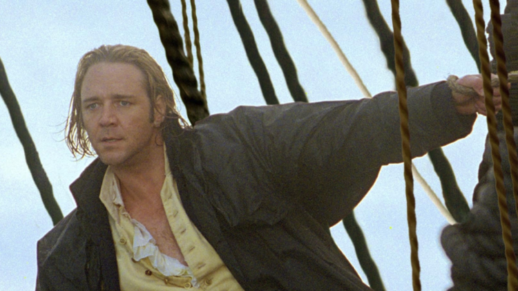 Person in vintage sailor outfit with yellow pants and ruffled shirt stands on ship deck, holding onto ropes.
