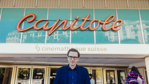 Person standing in front of the Capitole building with a "cinémathèque suisse" sign above the entrance.