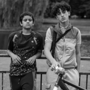 A black and white photo of two boys leaning against a railing