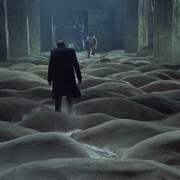 A man walks across piles of sand towards two men in the background.