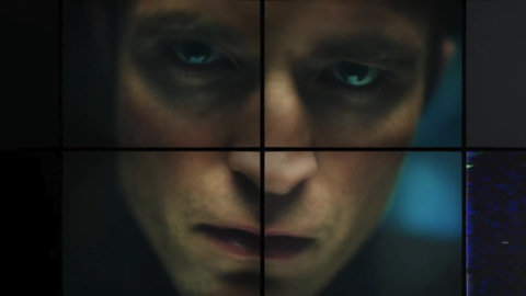 Close-up of a somber face with tired eyes, shown through a segmented, grid-like overlay with dark and blue tones.