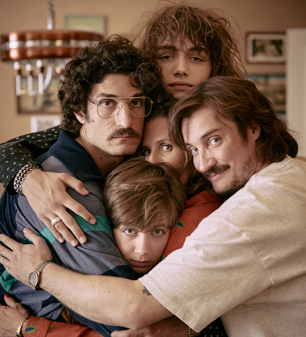 Five people closely embracing each other in a warm group hug inside a cozy room.