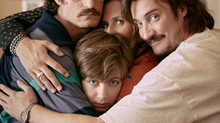 Five people closely embracing each other in a warm group hug inside a cozy room.