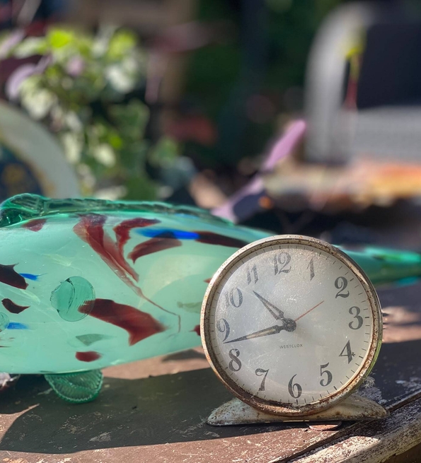 Objects from a 1960s Dominican front room including a green glass fish ornament and a small metal clock