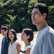 A group of four people stand on the shoreline looking out to the water