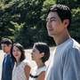 A group of four people stand on the shoreline looking out to the water