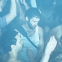 A crowded club dance floor with one person in a white vest looking down with their eyes closed