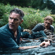A photo of two men chest deep in water wearing clothes.