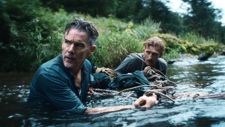 A photo of two men chest deep in water wearing clothes.
