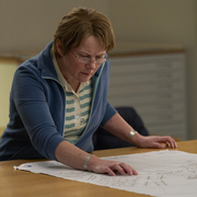 A still of a middle aged woman looking at a map.