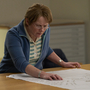 A still of a middle aged woman looking at a map.