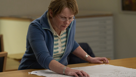 A still of a middle aged woman looking at a map.