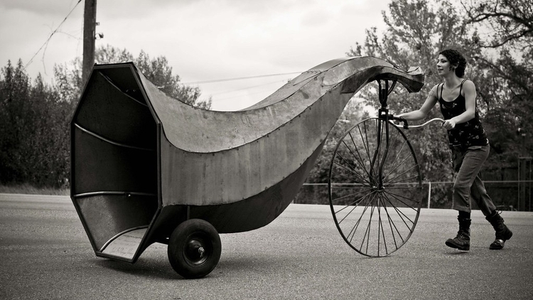 An image of Dominique Vyborna pushing a comically oversized horn on wheels.