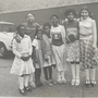 A black and white photograph of a group of children standing together smiling, posssibly from some time in the early 1970s