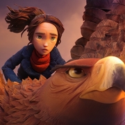 Animated young rider with tousled hair sits behind a large feathered bird, silhouetted by a warm sunset sky.
