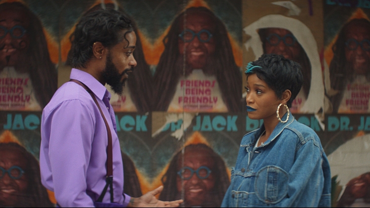 A man and a woman looking at each other standing in front of a wall of posters.